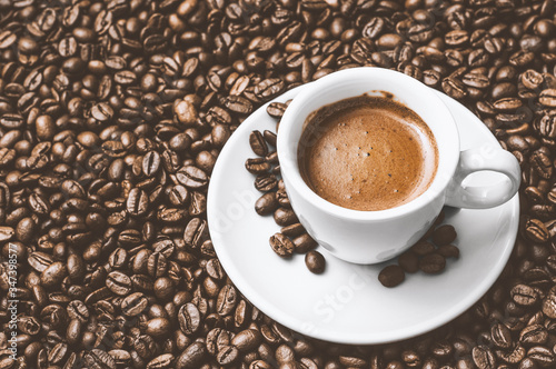 Coffee cup with a white saucer  on a brown coffee beans roasted grains background