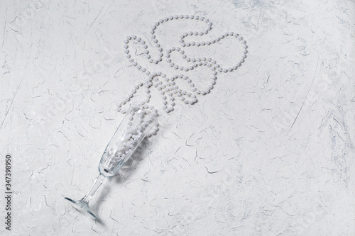 Holiday concept with wine glass and christmas decoration beads on shiny background with copy space. Top view.