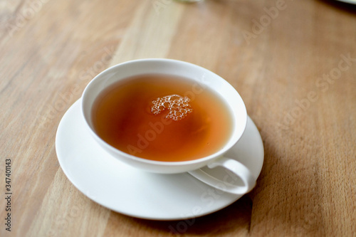 fresh cup of golden darjeeling tea on wooden breakfast table in white porcelain 
