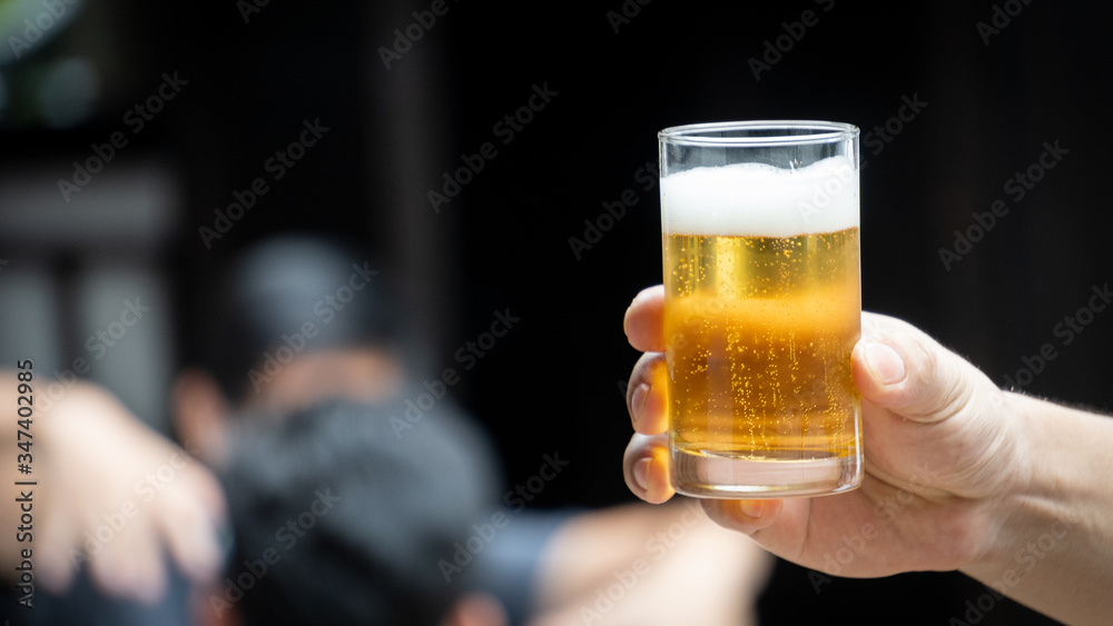 A glass of beer in the hand of a man who was about to drink with a blurred background A glass of beer in the hand of a man who was about to drink with a blurred background