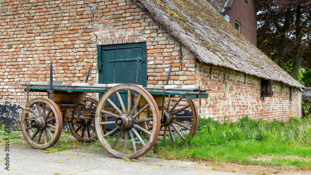 Traditional Dutch farm with thatched roof and an ancientwooden wagon