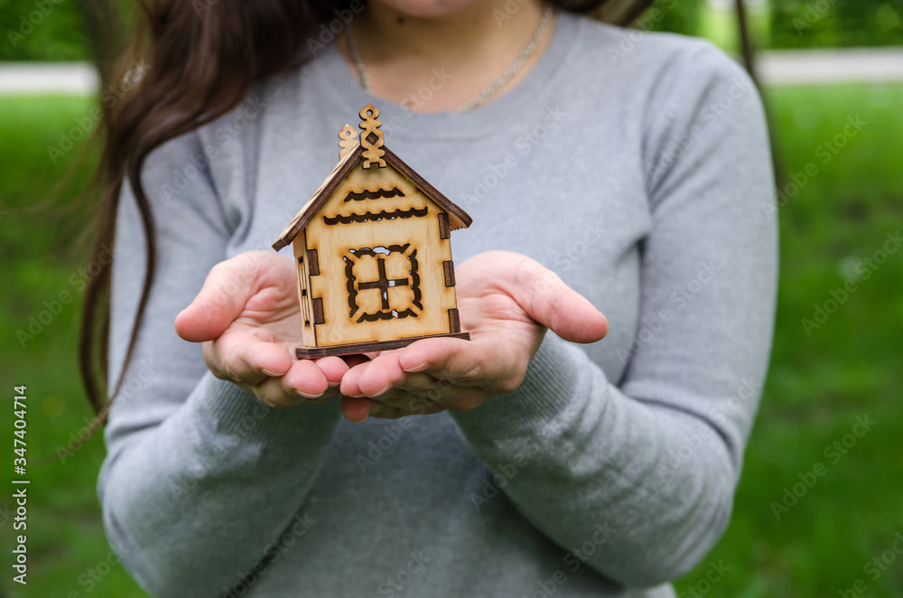 a small wooden house in female hands. a small wooden house in female hands.