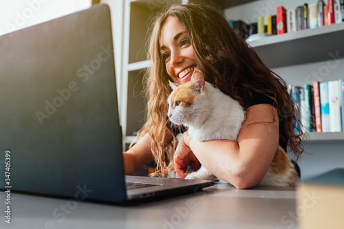 Giovane ragazza in smart woking con il gatto che le tiene compagnia 