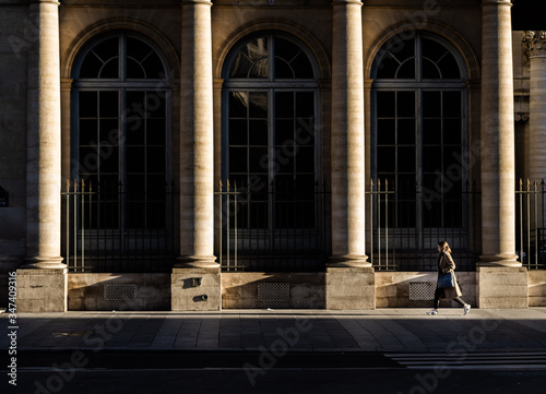 woman walking in front of a facade of a building with columns