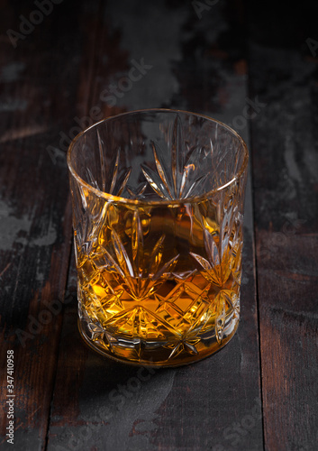 Single malt scotch whiskey in crystal glass on wooden background