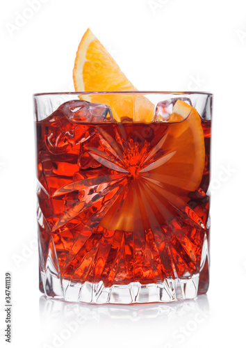 Negroni Cocktail in crystal glass with ice cubes and orange slice on white background with reflection.