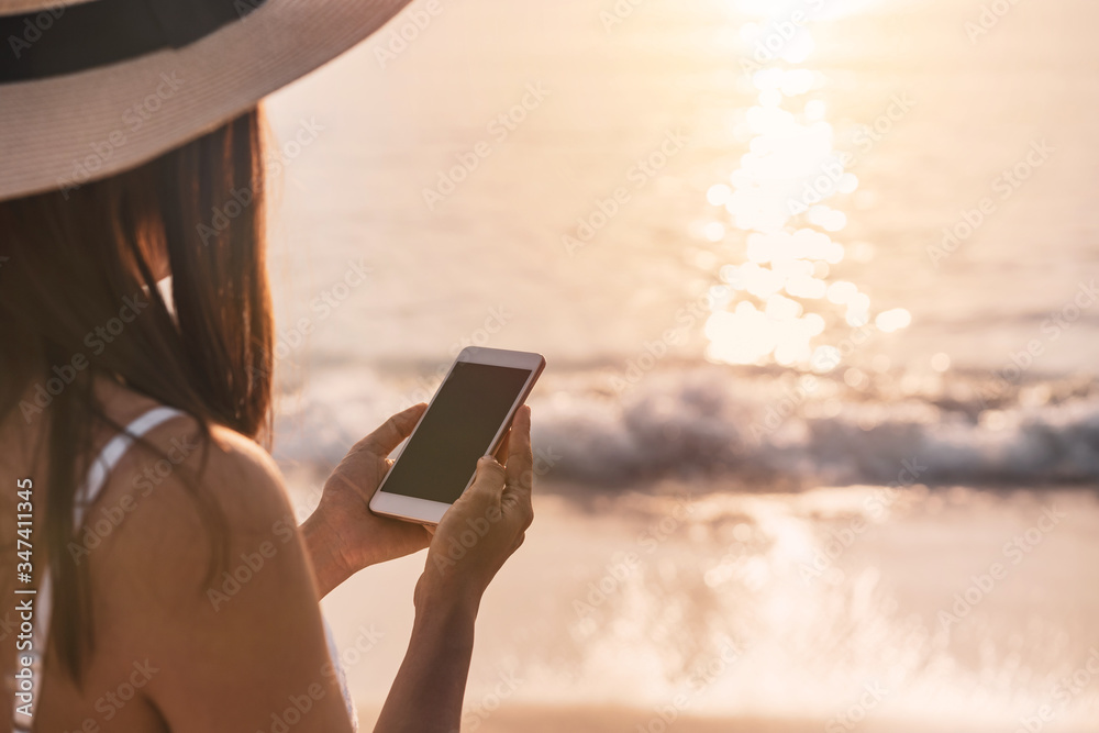 Young woman traveler using mobile phone on tropical beach at sunset, vacation and summer concept Young woman traveler using mobile phone on tropical beach at sunset, vacation and summer concept