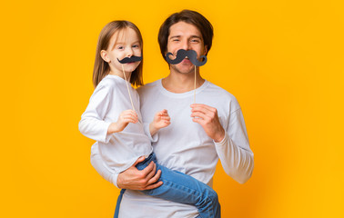 Portrait of father and daughter having fun over yellow background