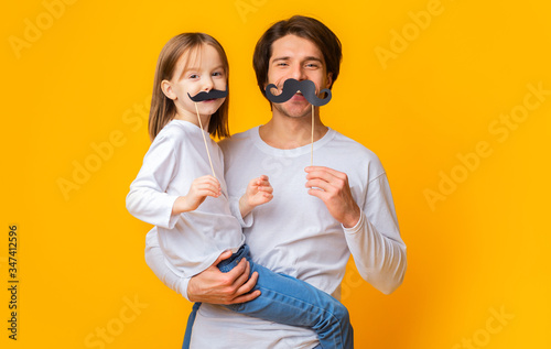 Portrait of father and daughter having fun over yellow background