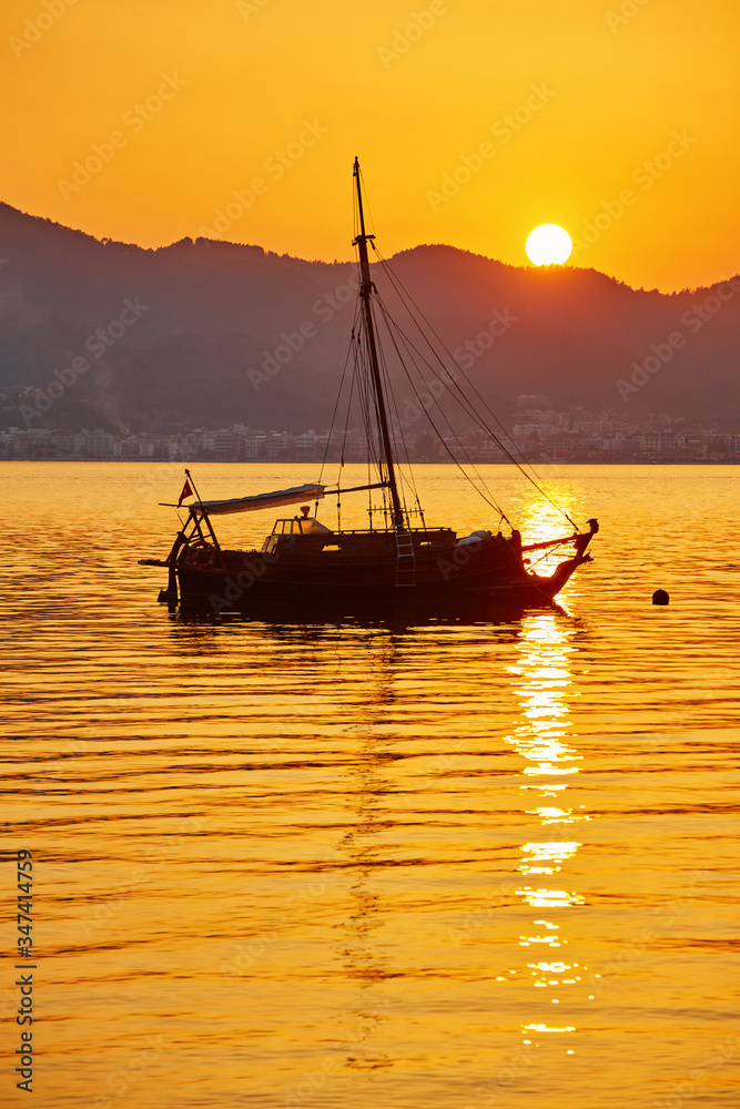 mountain and lonely motor boat reflected sunset in a calm sea, Marmaris