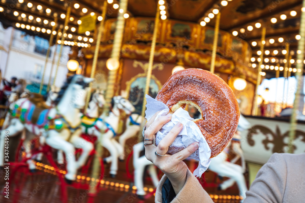 A sugary donut in front of an ancient German Horse Carousel built in 1896 in Navona Square, Rome, Italy