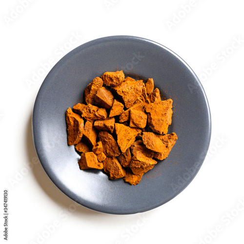 chaga mushroom. small dry chopped pieces of birch tree fungus chaga in a round plate isolated on a white background. concept of alternative natural medicine. square photo