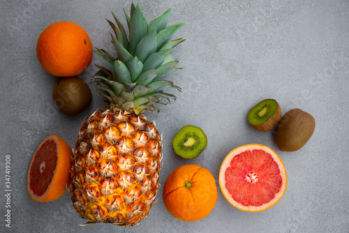 Ripe pineapple and other tropical fruit - orange  kiwi  grapefruit on grey background