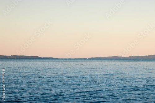 Distant blue adriatic sea with a tiny ferry ship far, outlines of islands meeting in the distance