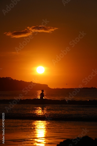 Atardecer en una playa, reflejo del sol sobre el mar. Persona cruzando por el reflejo del sol.