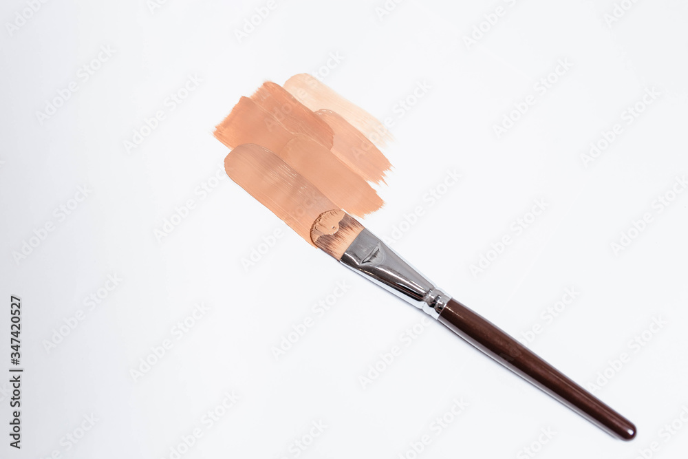 Beige liquid creamy foundation stroke smear and make-up brush isolated on white background, top view. BB cream or CC cream sample smudge, vertical. Beige liquid creamy foundation stroke smear and make-up brush isolated on white background, top view. BB cream or CC cream sample smudge, vertical.
