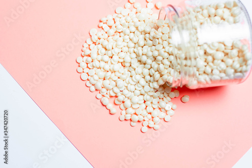 Wax for depilation of white pearl color and wooden stick spatula on pink background. Concept of waxing, smooth skin, bodycare, spa salon industry. Banner copy space, flyer, coupon