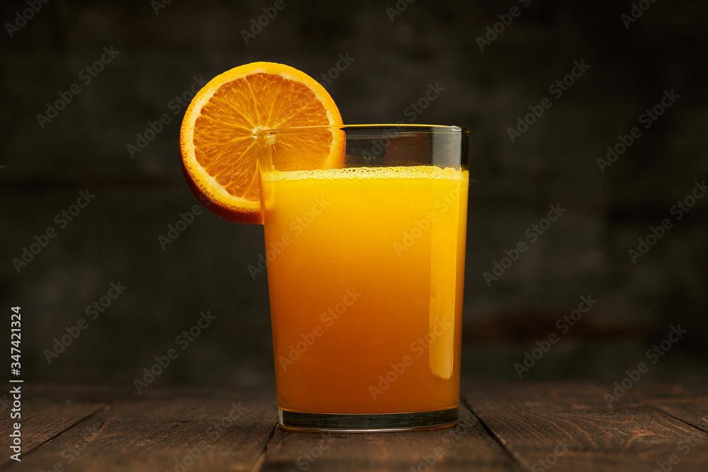 Fresh orange juice and fruit on a wooden table - natural and healthy food and drink. One glass of cocktail with a slice of fruit Fresh orange juice and fruit on a wooden table - natural and healthy food and drink. One glass of cocktail with a slice of fruit