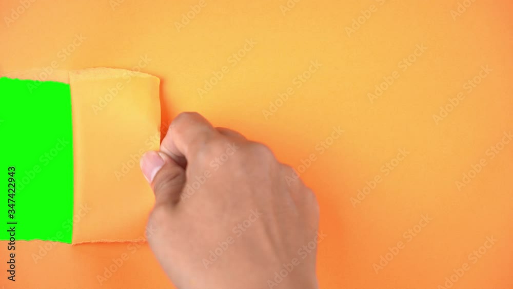 Man hand tears a paper and reveal green background