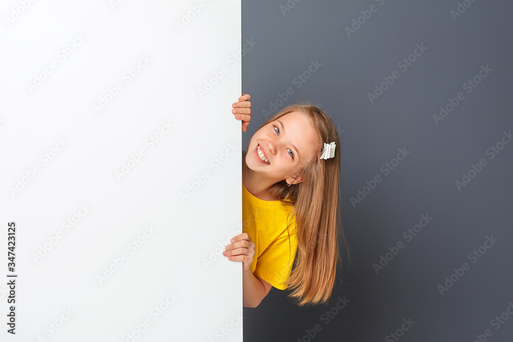 Funny teen girl in yellow clothes looks over a white wall, sign. Funny teen girl in yellow clothes looks over a white wall, sign.