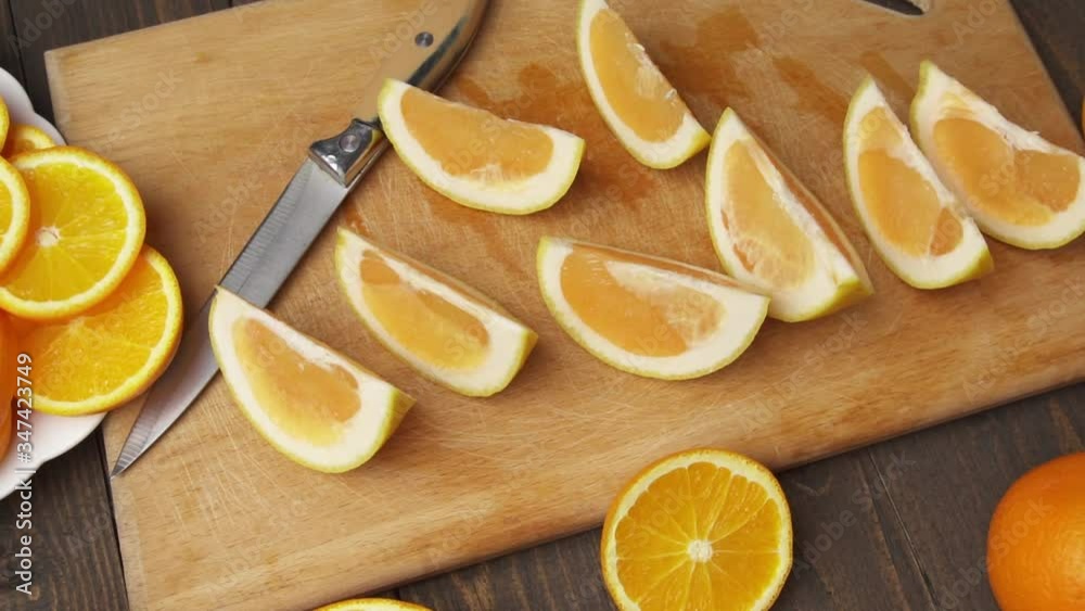 Fresh orange fruits on a wooden table, whole and sliced. A plate full of citrus slices.
Fresh orange fruits on a wooden table, whole and sliced. A plate full of citrus slices.