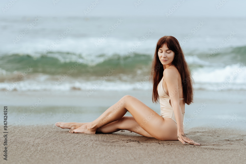 Outdoor summer fashion portrait of pretty sexy young woman in bikini posing behind blue ocean Outdoor summer fashion portrait of pretty sexy young woman in bikini posing behind blue ocean