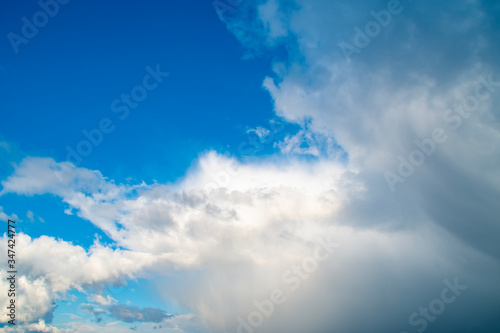 A large cloud is approaching a small one against a blue sky. Concept - it will rain soon, danger is coming.
