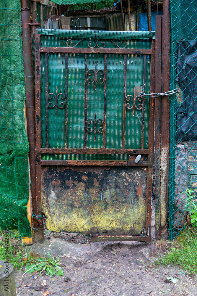 Old wrought iron gate of a house. Rusty and damaged door that leads to private property. Oxidation due to bad weather. Old wrought iron gate of a house. Rusty and damaged door that leads to private property. Oxidation due to bad weather.