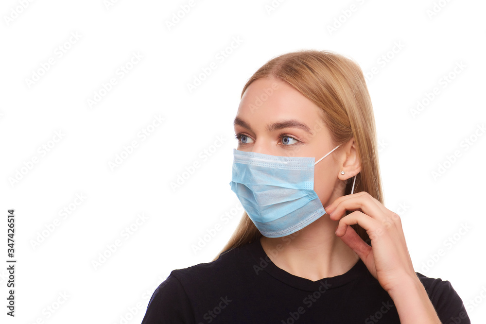blond young woman wearing medical mask adjusting it with her hands close up blond young woman wearing medical mask adjusting it with her hands close up