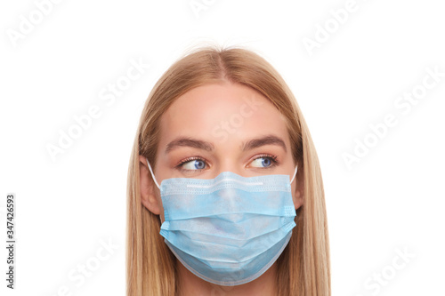 female face in a medical mask with eyes looks away