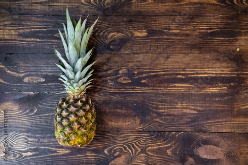 Pineapple is lying on a wooden table. View from the top. Vegetarian healthy food. Sweet fruit. Organic fruit. Closeup of yellow pineapple