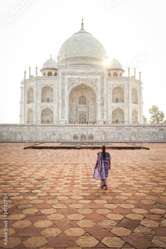 Woman wearing a blue sari looking at the Taj Mahal at sunrise