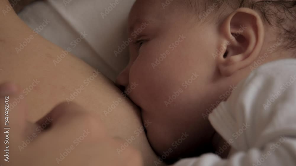 Woman Feeds Breast Milk To Her Newborn Baby Close Up While Lying In Bed Woman Feeds Breast Milk To Her Newborn Baby Close Up While Lying In Bed