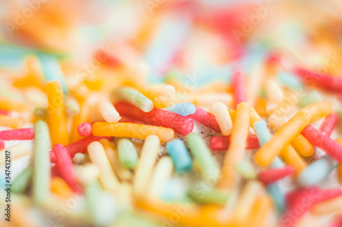 Multi-colored sweet pastry topping in white glaze decorates pastries. Close-up, macro shot.