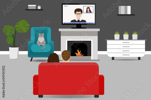 The family is sitting on the couch and watching the news on TV. Man, woman and cat in a room at home. Stay at home. Rest at home