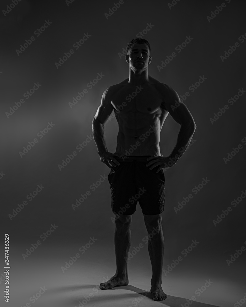 Naklejka premium Strong Athletic Man Fitness Model Torso showing six pack abs. isolated on dark background with copy-space