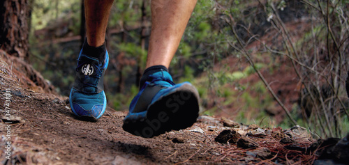 Trail running workout outdoors on rocky terrain, sports shoes detail on a challenging forest track