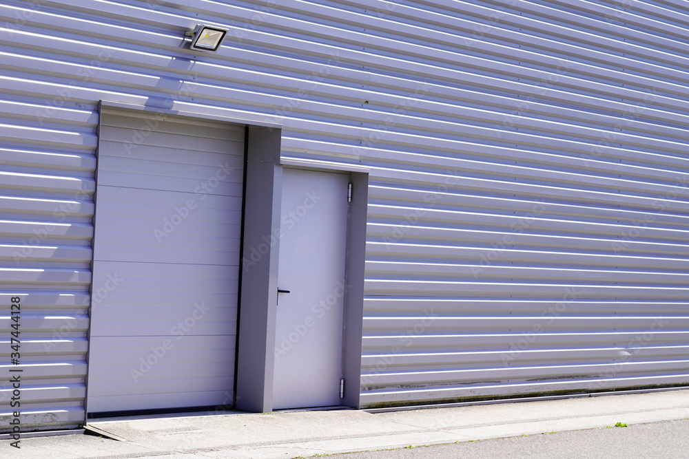 grey metal roll-down shutters on vertical profiled sheeting gray building fire exit door in commercial industrial unit grey metal roll-down shutters on vertical profiled sheeting gray building fire exit door in commercial industrial unit