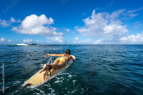 Beautiful slim girl surfer paddles on the wave in the open ocean. Mauritius Island