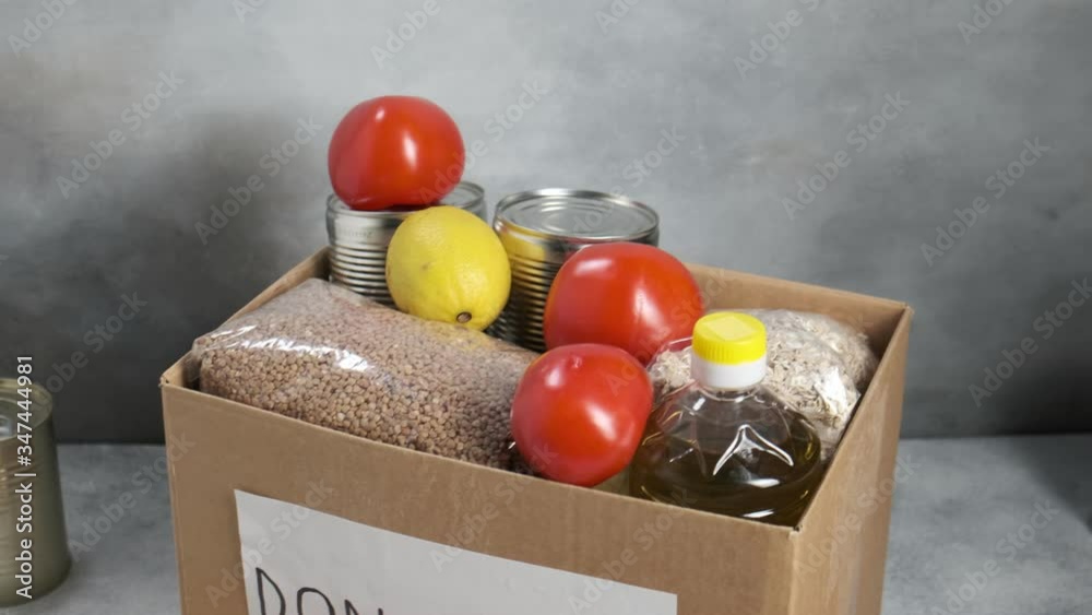 grocery food in carton donation box: vegetable oil, cereals, tomatoes, oranges, apples, tin cans, lemon. Coronavirus relief fund, christmas charity, delivery, volunteer help during Covid-19 quarantine grocery food in carton donation box: vegetable oil, cereals, tomatoes, oranges, apples, tin cans, lemon. Coronavirus relief fund, christmas charity, delivery, volunteer help during Covid-19 quarantine