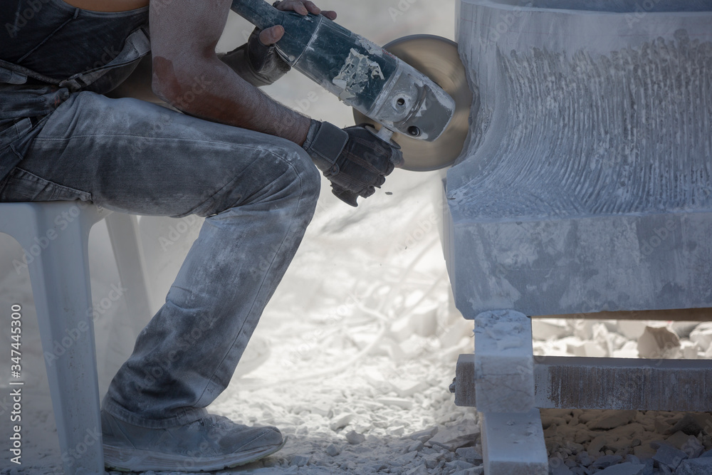 sculptor cutting stone with grinder