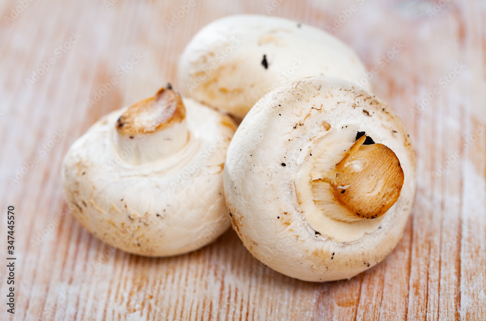 Raw white champignons on wooden surfacen  in kitchen