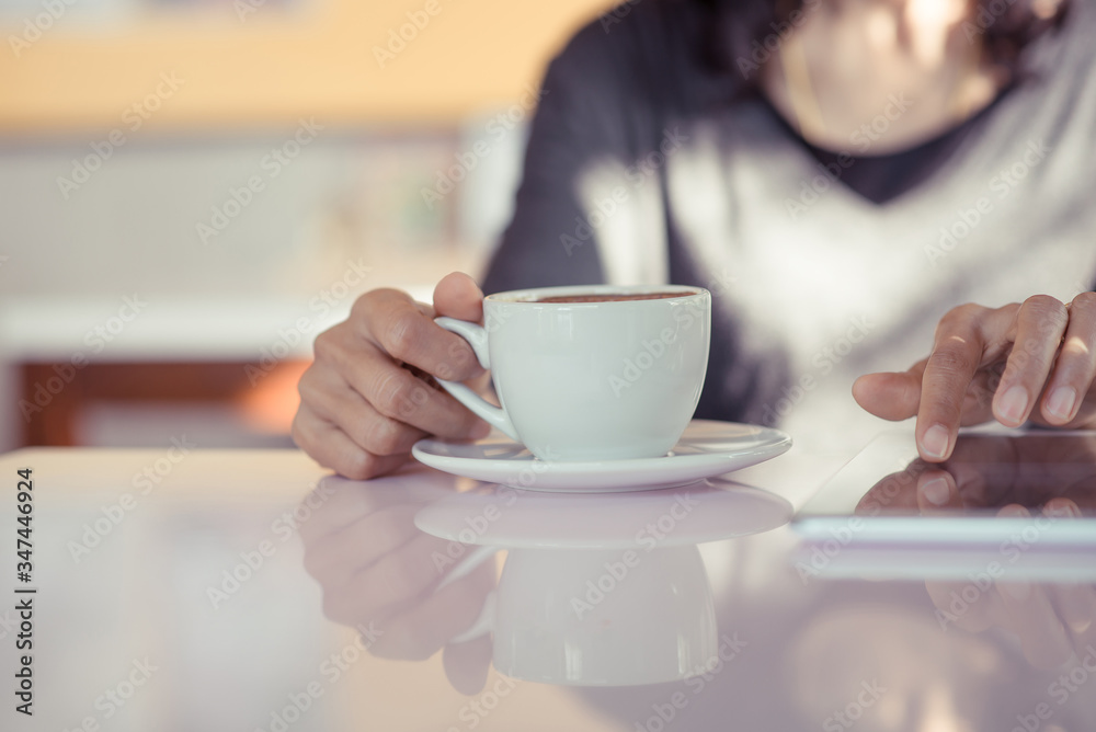 Young woman holding a cup of coffee while using smartphone close up. Young woman holding a cup of coffee while using smartphone close up.