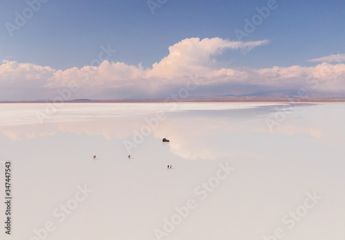 Couple in Salt Flats Uyuni Bolivia. Romantic tourists on beautiful mirror reflection on blue sky and cloud. DRONE Shot in Salar de Uyuni salt flat. Holiday, love, adventure vacation honeymoon travel © Jam Travels