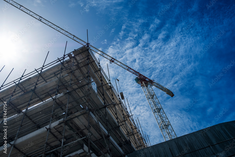 Building site with scaffolding and construction crane. Concrete building under construction Building site with scaffolding and construction crane. Concrete building under construction