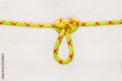 Butterfly loop knot tied on new colored, green rope for personal belaying. Alpine lineman's loop is an excellent mid-line rigging knot. Self-insurance mustache. Isolated on white background