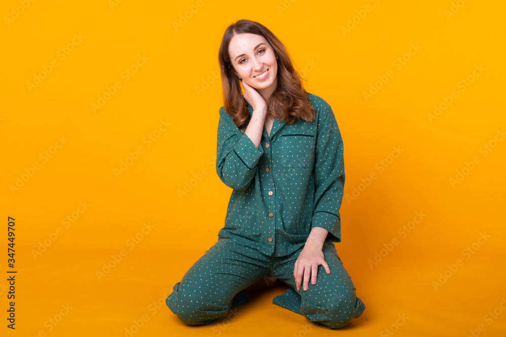 Smiling young girl in pajamas home wear posing while resting at home isolated on yellow background studio portrait. Relax good mood lifestyle concept. Smiling young girl in pajamas home wear posing while resting at home isolated on yellow background studio portrait. Relax good mood lifestyle concept.