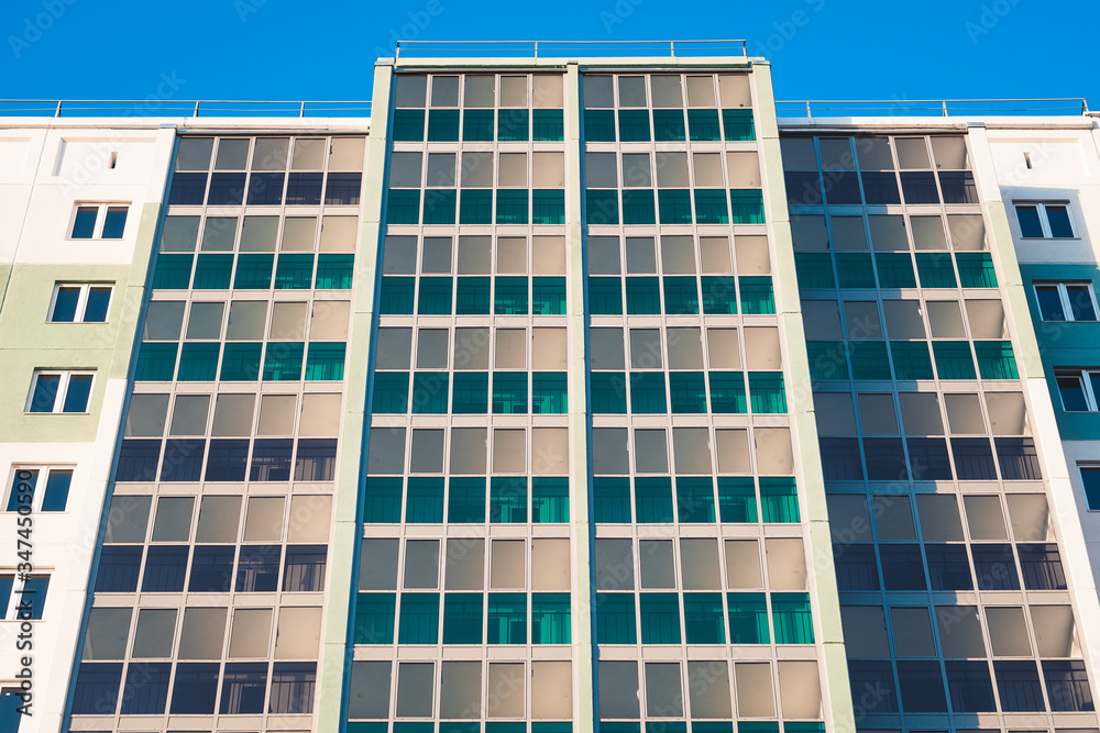 Close-up - part of new multistorey panel home with balconies and windows, new building in sunlight.