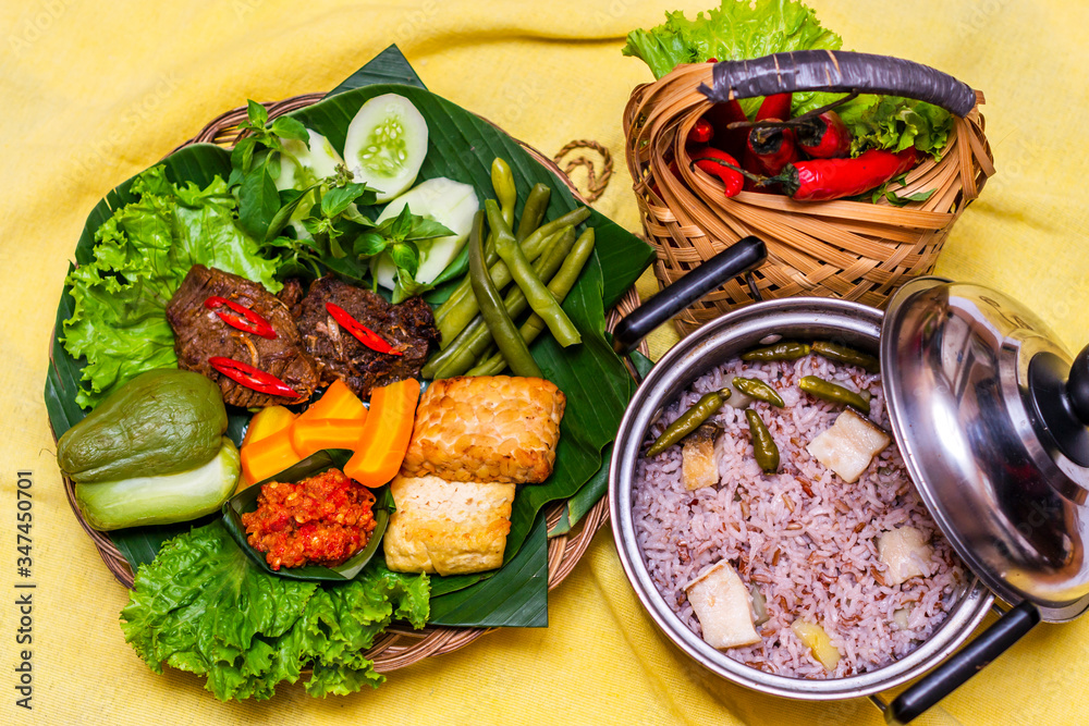 Indonesian traditional food nasi liwet with empal daging, tahu, sambal ...