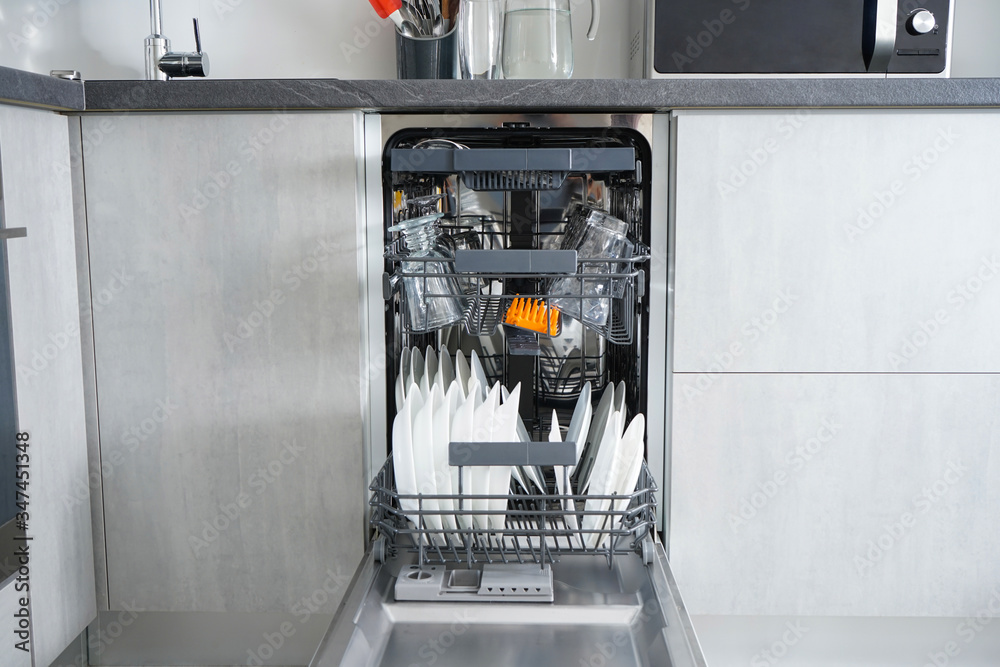 Dishwasher, open and loaded with dishes in the kitchen, after washing. Dishwasher, open and loaded with dishes in the kitchen, after washing.